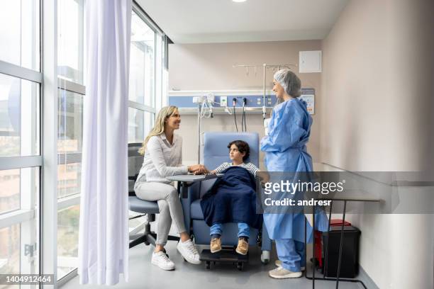 nurse talking to a mother at the hospital while getting chemotherapy for her son - iv infusion stockfoto's en -beelden
