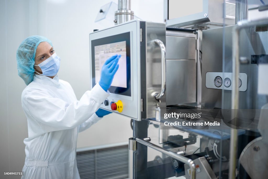 Mujer que usa el equipo adecuado visto en la fabricación farmacéutica
