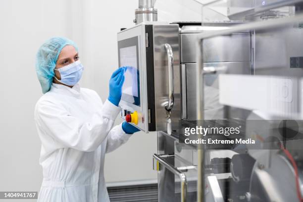 woman wearing proper equipment seen in pharmaceutical manufacturing - cleanroom stock pictures, royalty-free photos & images