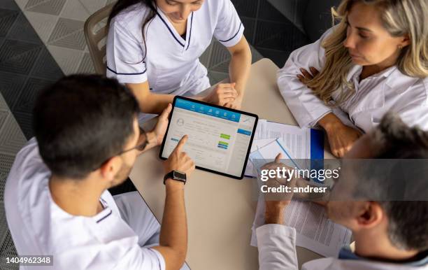 equipe de médicos em uma reunião discutindo o prontuário de um paciente - registo-médico-eletrónico - fotografias e filmes do acervo