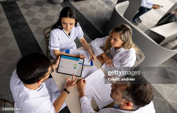 group of healthcare workers in a meeting dicussing a patient's diagnosis - medisch dossier stockfoto's en -beelden