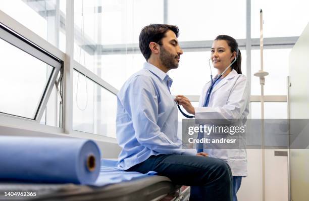 doctora examinando a un paciente en su consultorio - hombre revision fotografías e imágenes de stock