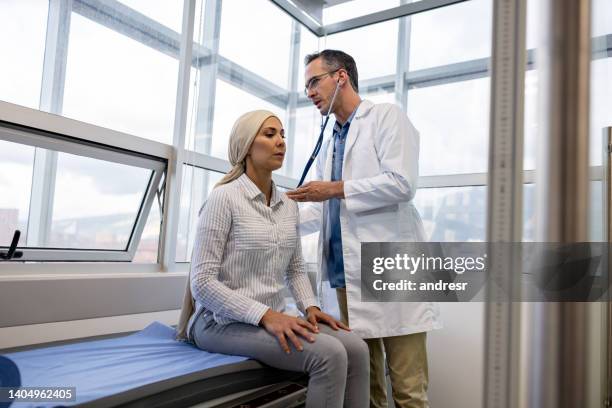 doctor listening to the heartbeat of a cancer patient on a consultation - oncologist stock pictures, royalty-free photos & images
