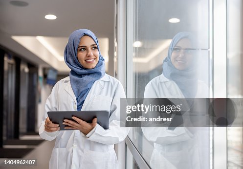 Feliz médico musulmán que trabaja en el hospital usando una tableta Feliz médico musulmán que trabaja en el hospital usando una tableta