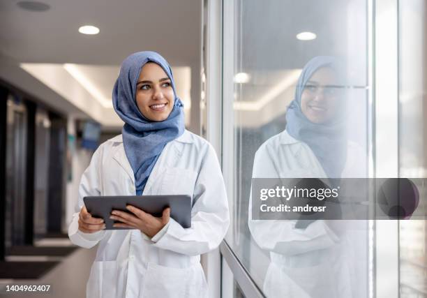 feliz médico musulmán que trabaja en el hospital usando una tableta - islamismo fotografías e imágenes de stock