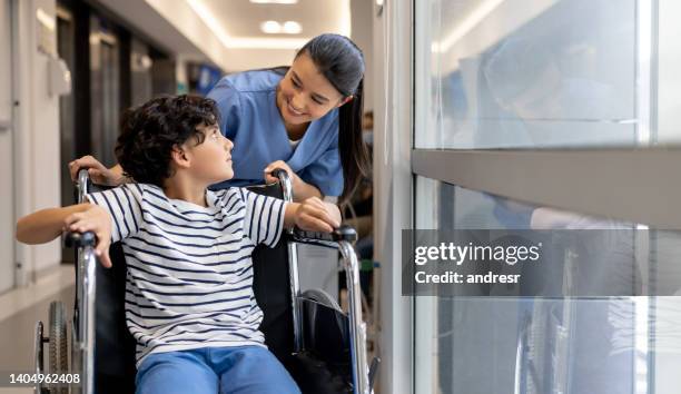 nurse taking care of a young patient in a wheelchair at the hospital - nurse leaving stock pictures, royalty-free photos & images