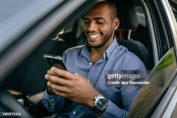 mann mit smartphone im geparkten auto - auto blau stock-fotos und bilder