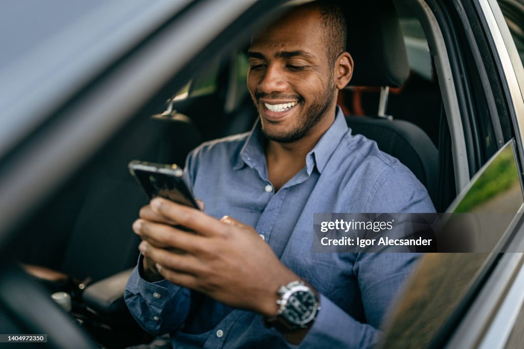 Homem usando smartphone em carro estacionado