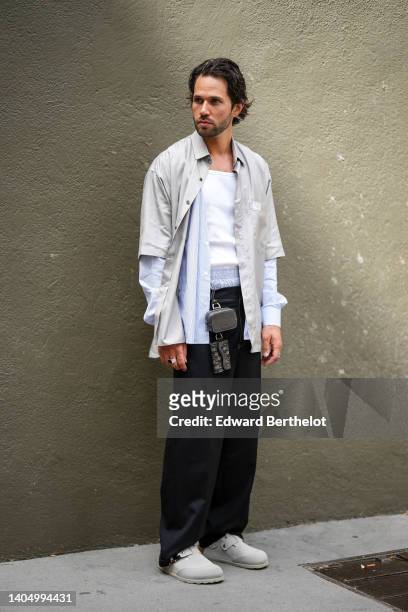 Jean-Sebastien Rocques wears a white ribbed tank-top, a baby blue boxer, a pale gray short sleeves shirt from Dior, a baby blue and white striped...