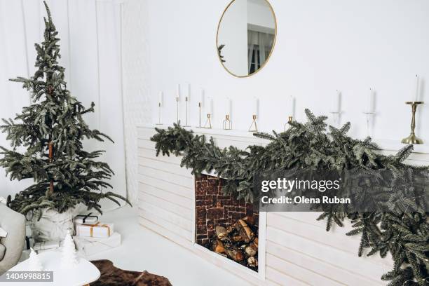 xmas tree branches, fireplace with firewood and garland. - garland stock pictures, royalty-free photos & images