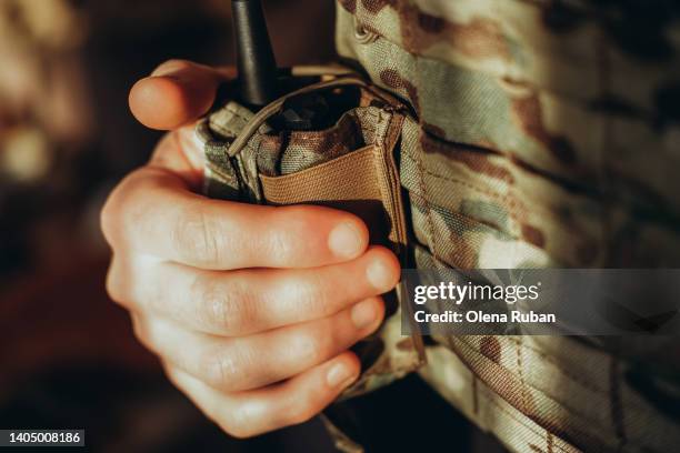 female hand holding walkie-talkie in tactical load bearing vest. - army stock-fotos und bilder