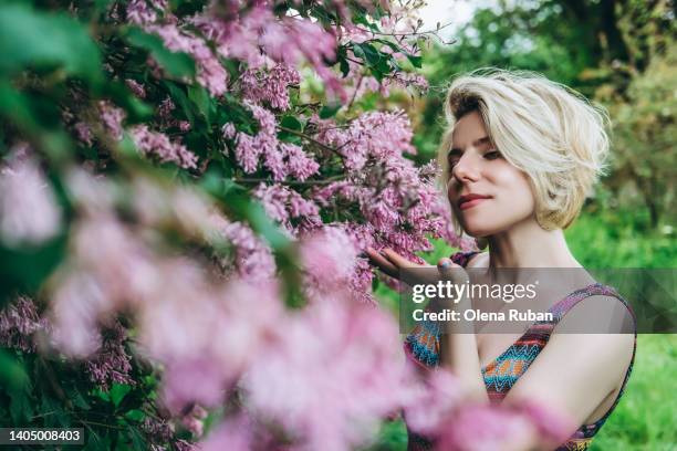 young woman inhaling aroma of lilac flowers. - garden of dreams foundation press conference stockfoto's en -beelden