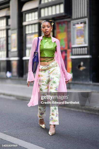 Guest wears gold hair fringed hair clips, a green ribbed shiny high neck / cropped / laces waist t-shirt, a pale pink long kimono, gold bracelets,...