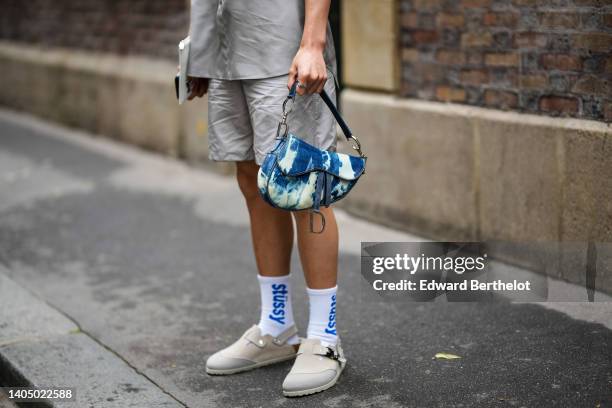 Guest wears a pale gray / silver silk short sleeves shirt, matching gray silver shiny satin shots, a blue and white tie and dye print pattern Saddled...