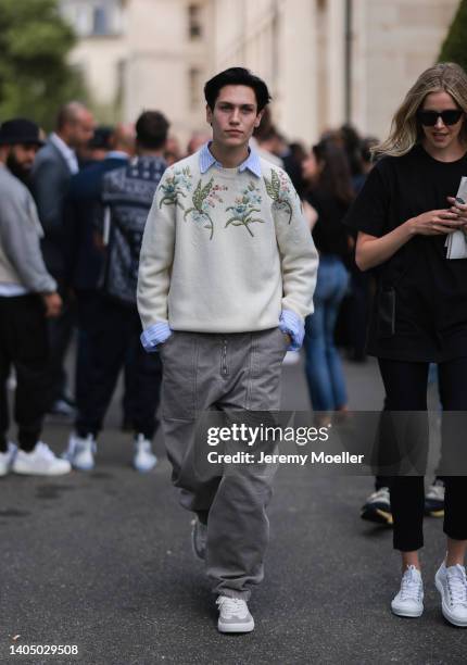 Chase Hudson seen wearing a blue striped shirt blouse, a creme beige floral embroidered knit pullover/sweater, a grey jeans denim cargo pants and...