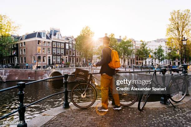 man with a bike on a sunny day in amsterdam, netherlands - amsterdam bike stockfoto's en -beelden