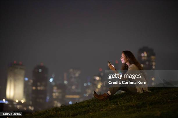 woman speaking on phone outdoors in front of cityscape - israelischer abstammung stock-fotos und bilder