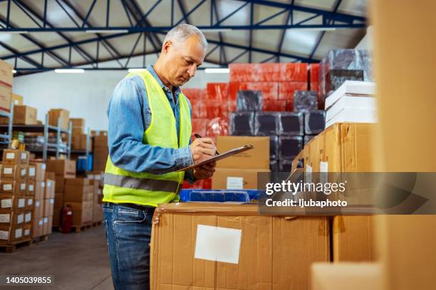 hombre caucásico escribiendo en el portapapeles en el almacén - orden de compra fotografías e imágenes de stock