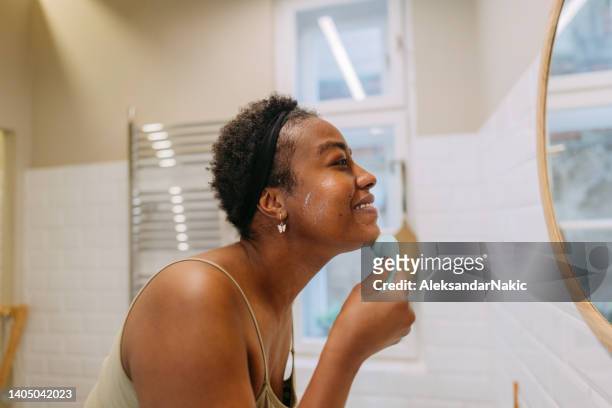 young woman washing her face in a bathroom - washing face stock pictures, royalty-free photos & images