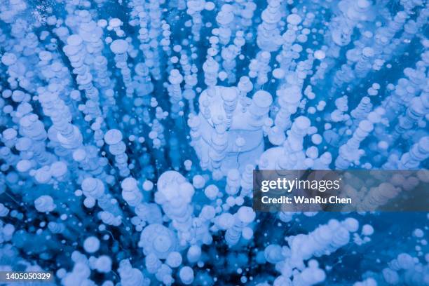 gas bubbles texture in ice of lake baikal. winter background - methaan stockfoto's en -beelden