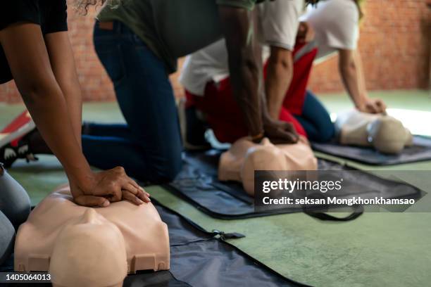 group of adult education students practitcing cpr chest compressioon on a dummy. - cpr stock pictures, royalty-free photos & images