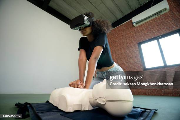 young woman using virtual reality headset for online cpr training. - virtual reality classroom stock pictures, royalty-free photos & images