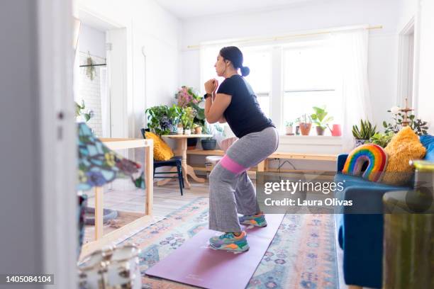 young adult woman exercising in her apartment - heimtraining stock-fotos und bilder