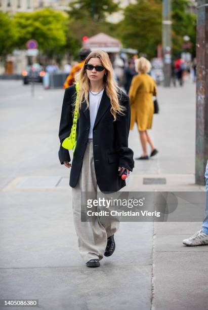 Guest is seen wearing black oversized blazer, neon Balenciaga bag, grey wide leg pants outside Craig Green during Paris Fashion Week - Menswear...
