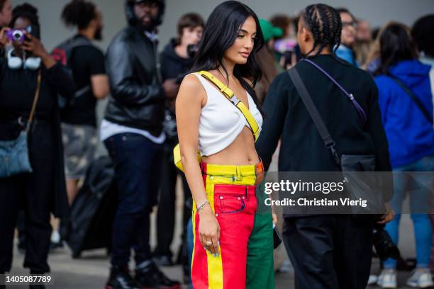 Amina Muaddi seen wearing multi colored pants, white cropped top, yellow bag outside Loewe during Paris Fashion Week - Menswear Spring/Summer 2023 on...