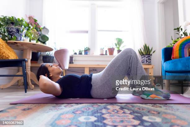 young adult woman exercising in her apartment - abs stock pictures, royalty-free photos & images