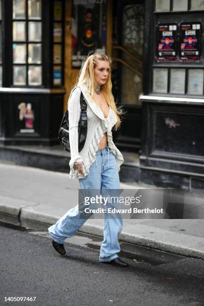Guest wears a white cut-out pattern in macrame ruffled V-neck / long sleeves / asymmetric gilet, a black shiny leather shoulder bag from Guess, blue...