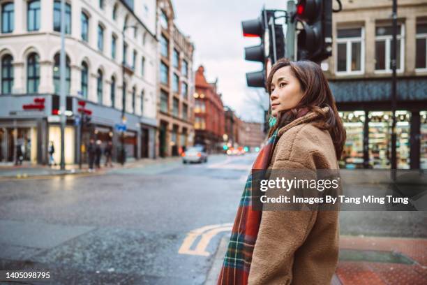 young asian female traveller waiting for traffic signal while exploring in downtown street in a town - road signal ストックフォトと画像