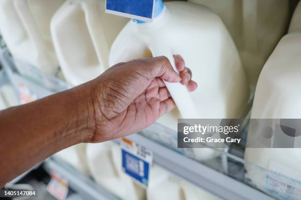 woman grabs gallon of milk at supermarket - gallon stockfoto's en -beelden