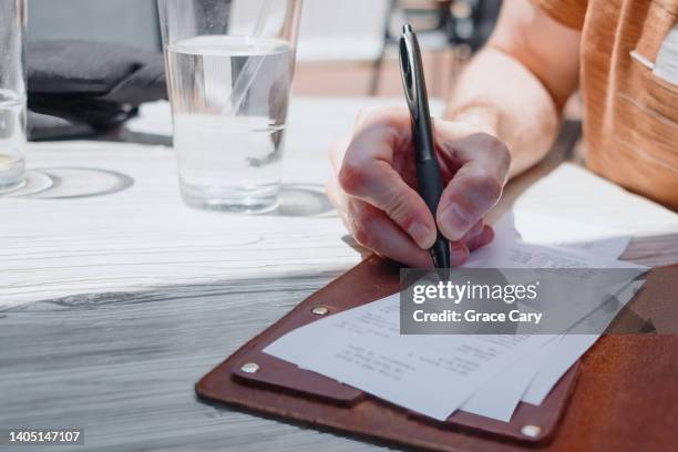 man leaves tip on credit card at restaurant - gratuity - fotografias e filmes do acervo