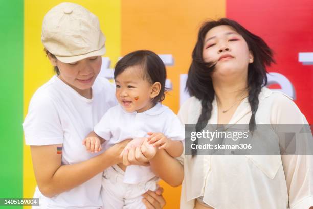 close up candid positive emotion moment asian lgbt family leisure around rainbow backdrop on pride month parade - human rights of children stock-fotos und bilder