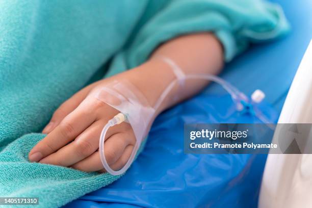 hand of the patient is on drip receiving a saline solution on bed vip room at hospital. medical concept. - hospital bed with iv stock pictures, royalty-free photos & images