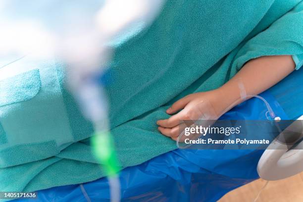 a sick patient lies on the bed, is on drip receiving a saline solution on bed vip room at hospital. medical concept. - circulatory system hand fotografías e imágenes de stock