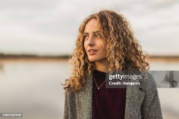 happy blonde curly beautiful girl in coat against sky. charming smile. close up portrait. spring break. woman enjoying vacation. visit local attractions. girl in nature. feel happiness. - spring flowing water stock pictures, royalty-free photos & images