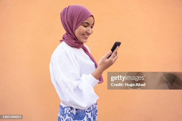 young arab woman smiling with her mobile phone. - arabic people stockfoto's en -beelden