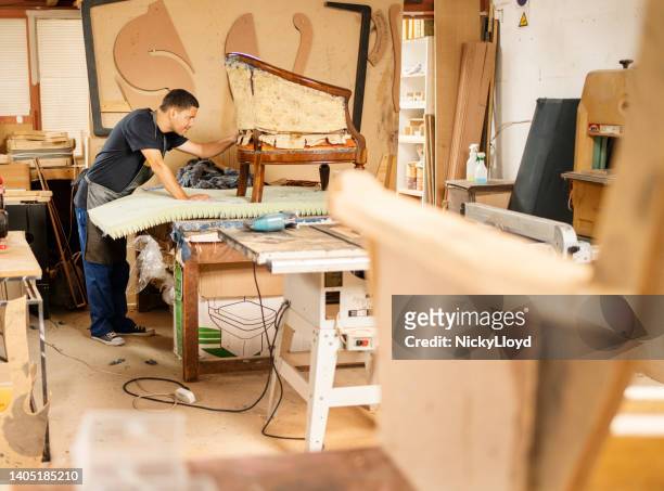 worker reupholstering a chair on a workshop bench - upholstered furniture stock pictures, royalty-free photos & images