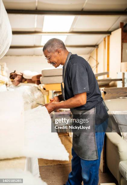 upholstery worker cutting foam in a furniture workshop - renovation of upholstered furniture stock pictures, royalty-free photos & images