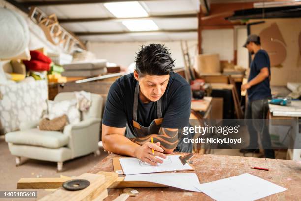 worker sketching designs at a bench in furniture making workshop - upholstry stockfoto's en -beelden