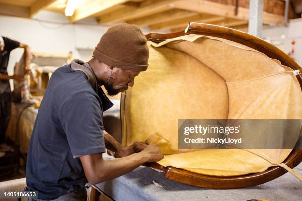 worker attaching fabric to a chair in a furniture making shop - upholstered furniture stock pictures, royalty-free photos & images