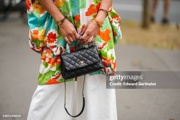 Guest wears a white with green / orange / blue flower print pattern short sleeves kimono, white wide legs pants, a black shiny leather Trendy CC...