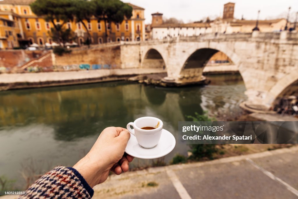 Man drinking espresso by the Tiber river in Trastevere neighbourhood, Rome, Italy