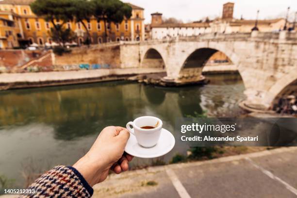 man drinking espresso by the tiber river in trastevere neighbourhood, rome, italy - italian cafe culture stock pictures, royalty-free photos & images
