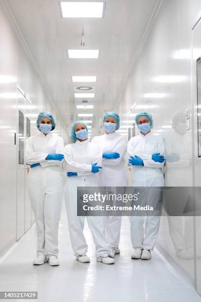 voll ausgestattete arbeiterinnen im flur der pharmafabrik stehend gesehen - cleanroom stock-fotos und bilder