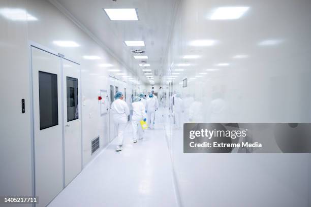 workers in protective equipment in the pharmaceutical industry seen on shift in the hallway of the production plant - cleanroom stockfoto's en -beelden