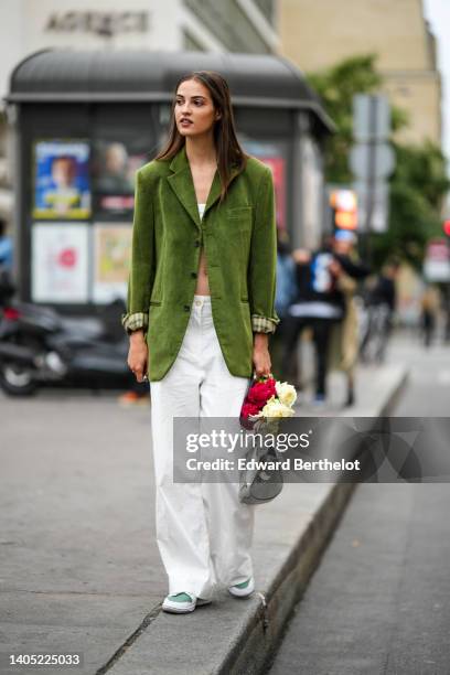 Model wears a white shoulder-off / cropped top, a green ripped velvet long blazer jacket, white large wide legs pants, a silver shiny varnished...