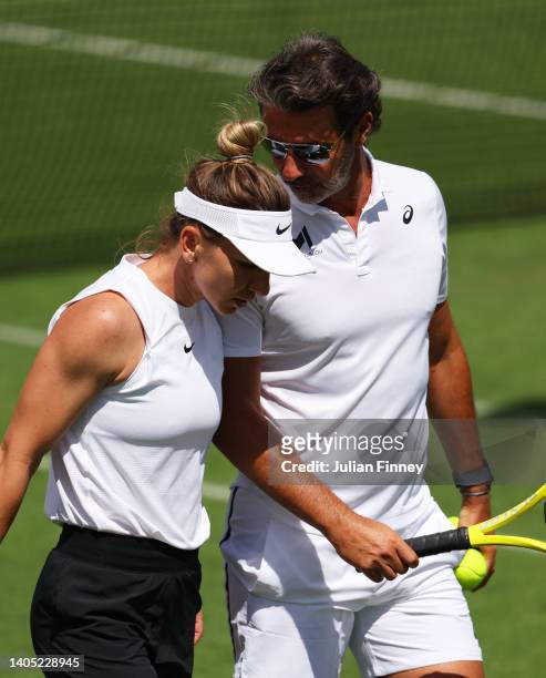 Simona Halep of Romania speaks to their coach Patrick Mouratoglou look on during a practice session ahead of The Championships Wimbledon 2022 at All...